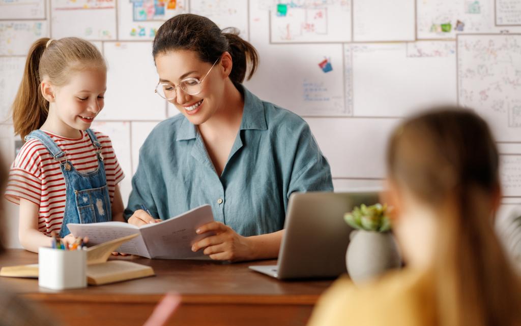 Student with a teacher at the teacher's desk