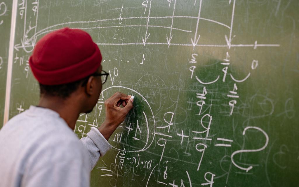 Student solving an equation on a blackboard